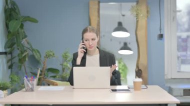 Displeased Young Businesswoman Talking Angrily on Smartphone at Work