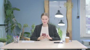 Young Businesswoman Browsing Internet on Smartphone in Office