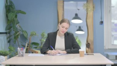Young Businesswoman Writing while Sitting in Office