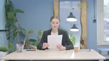 Young Businesswoman Reading Documents in Office, Paperwork