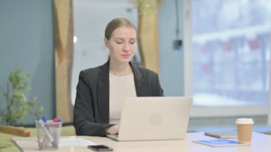 Young Businesswoman Looking at Camera while using Laptop