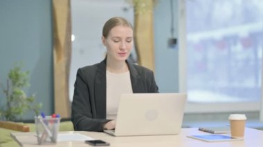 Young Businesswoman Smiling at Camera while using Laptop
