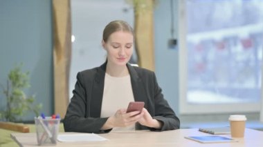 Young Businesswoman Browsing Internet on Smartphone in Office