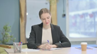 Young Businesswoman Writing while Sitting in Office