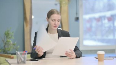 Young Businesswoman Reading Documents in Office, Paperwork