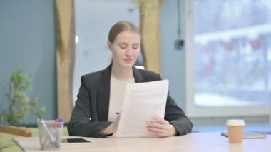 Young Businesswoman Celebrating Success while Reading Documents in Office