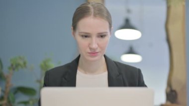 Close Up of Young Businesswoman Looking at Camera while using Laptop