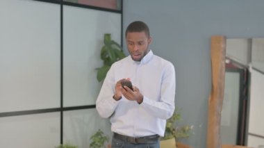 Excited African American Man Celebrating Win on Smartphone
