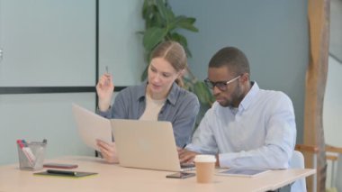 African American Man and Businesswoman Discussing Paperwork in Office