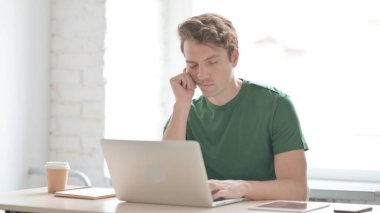 Yorgun genç adam çalışırken uyuyor.