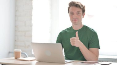 Dizüstü bilgisayarda Çalışan Gelişigüzel Genç Adam 'dan Baş Parmakla