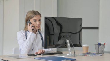 Masaüstü Bilgisayarında Çalışırken Telefonda Konuşan Bayan Doktor