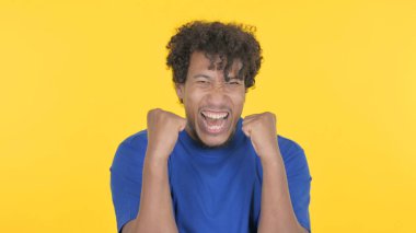 Successful Casual African Man Celebrating Achievement on Yellow Background