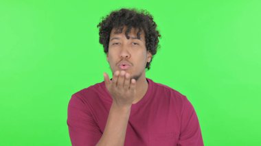 Casual African Man Giving Flying Kiss on Green Background