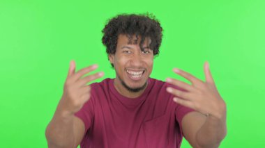 Pointing Casual African Man Inviting on Green Background