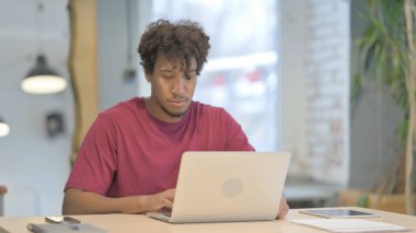 Pensive Young African Man Working on Laptop