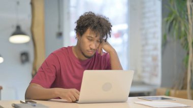 Dizüstü bilgisayarla uğraşırken uyuyan yorgun Afrikalı genç adam