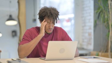 Genç Afrikalı Adam dizüstü bilgisayarla uğraşırken baş ağrısı çekiyor