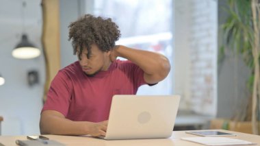 Young African Man having Neck Pain while using Laptop