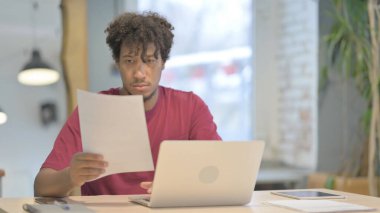 Young African Man Working on Laptop and Documents