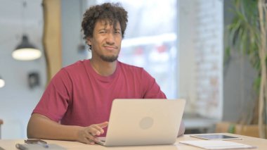 Young African Man Shaking Head in Rejection while Working on Laptop