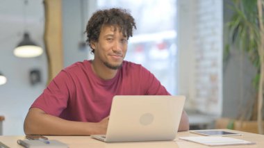 Young African Man Shaking Head in Acceptance While Working on Laptop