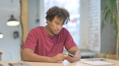 Young African Man Browsing Internet on Smartphone in Office