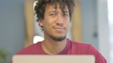Close Up of Young African Man Shaking Head in Rejection while Working on Laptop