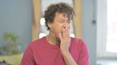 Portrait of Young African Man Yawning while Sitting in Creative Place