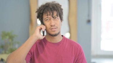 Young African Man Talking on Phone to Discuss Work