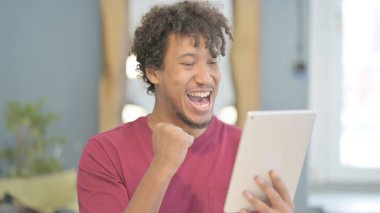 Young African Man Cheering Success on Digital Tablet
