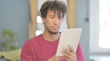 Young African Man Browsing Internet on Digital Tablet