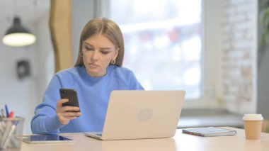 Laptop kullanırken Smartphone kullanan Genç Kadın