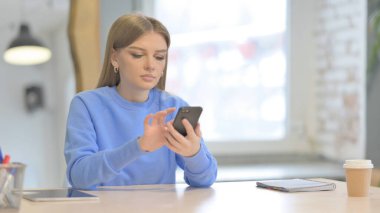 Young Woman Browsing Internet on Smartphone in Office