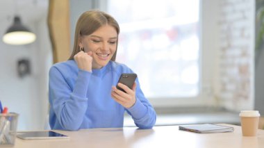 Successful Young Woman Celebrating Win on Smartphone