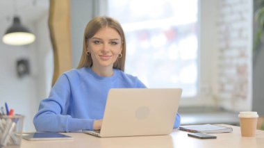 Young Woman Shaking Head in Approval While Working on Laptop