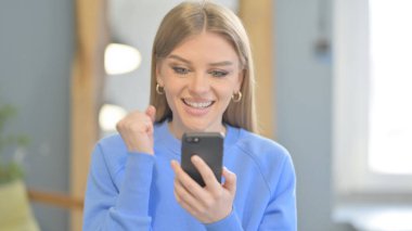Excited Young Woman Celebrating Win on Smartphone