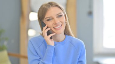Young Woman Talking on Phone to Discuss Work