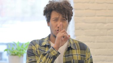 Young African Man with Finger on Lips, Silence Yellow Screen