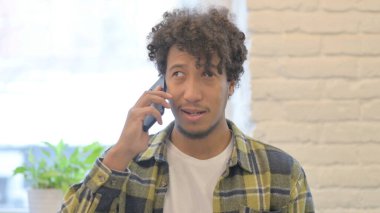 Young African Man Talking on Phone to Discuss Work