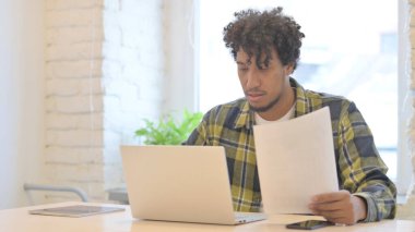 Young African Man Working on Laptop and Documents