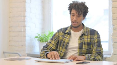 Young African Man Coming Back to Office and Opening Laptop