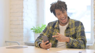 Happy Young African Man Celebrating Win on Smartphone