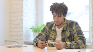 Young African Man Shopping Online by Using Smartphone
