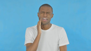 Young African Man with Toothache on Blue Background