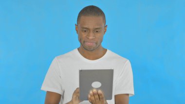 Young African Man using Digital Tablet on Blue Background