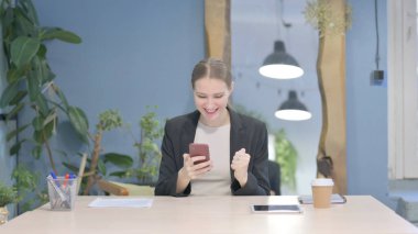 Successful Young Businesswoman Celebrating Win on Smartphone
