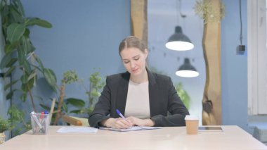Young Businesswoman Writing while Sitting in Office