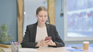 Young Businesswoman Browsing Internet on Smartphone in Office