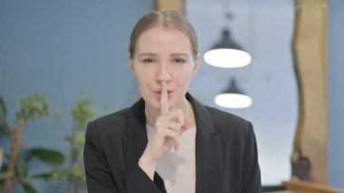 Young Businesswoman with Finger on Lips, Asking for Silence